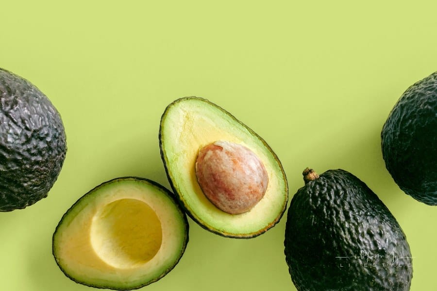 Fresh organic hass avocados on a green background, top view with copy space