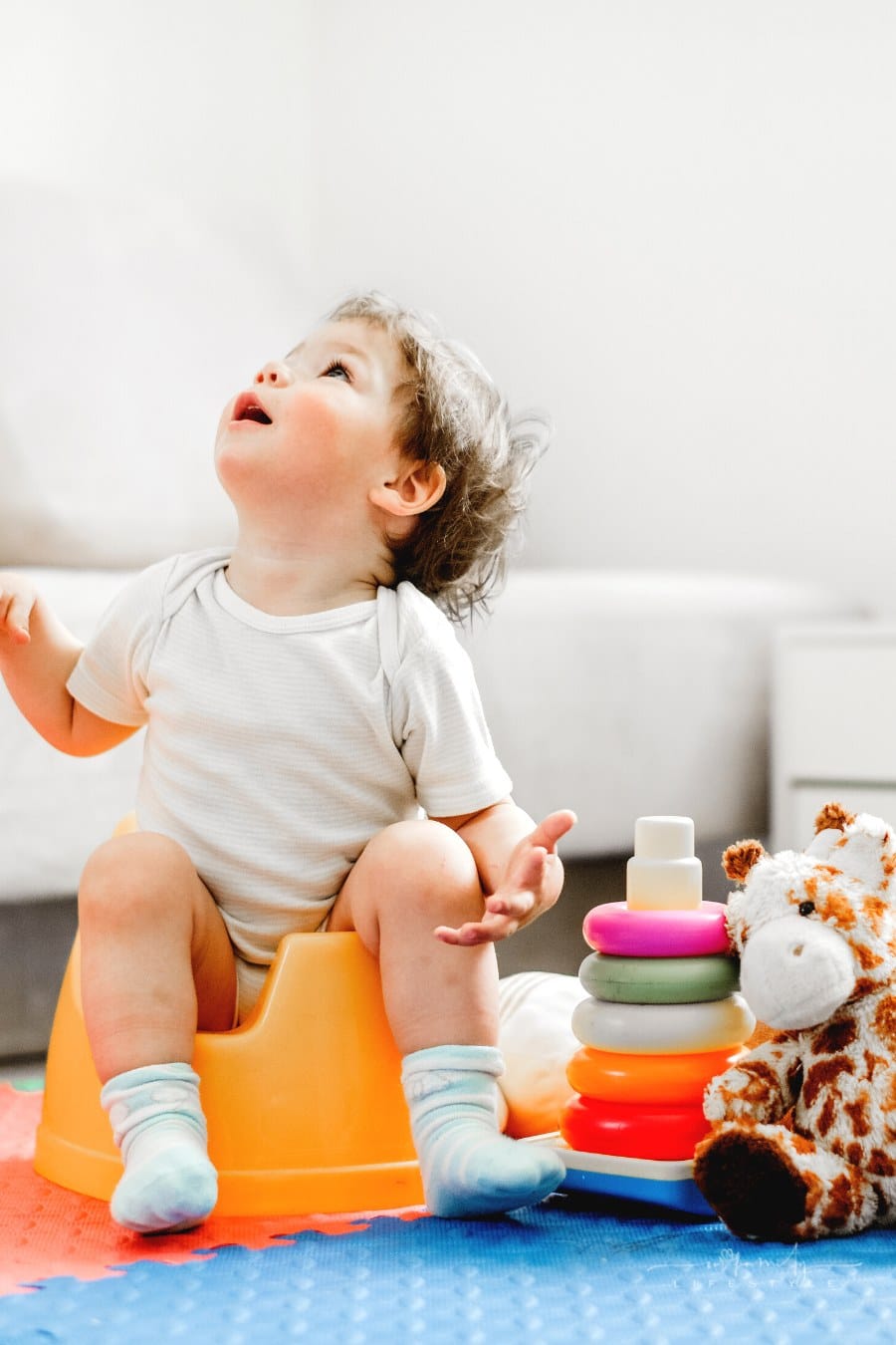 young toddler sitting on plastic training potty