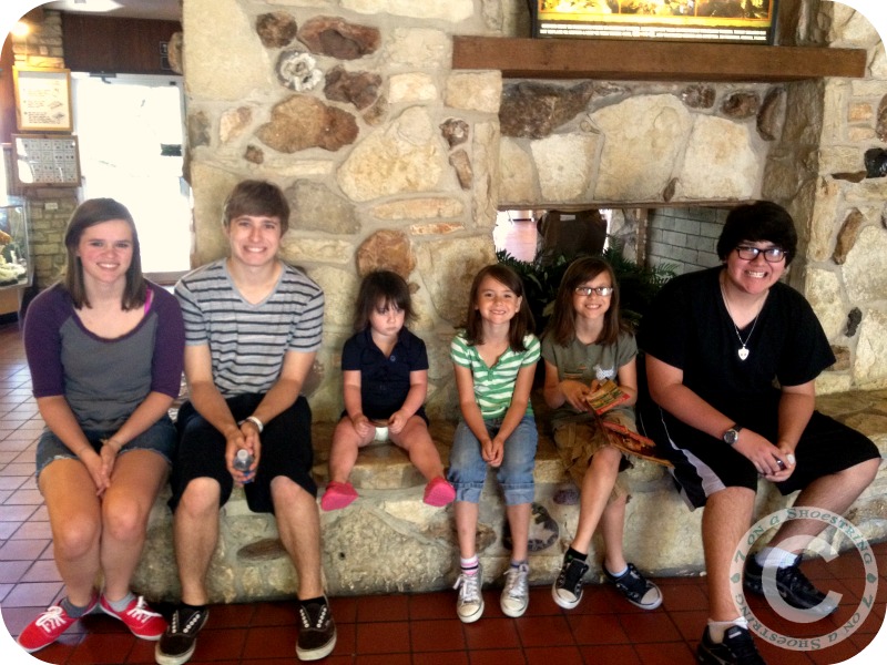kids and teens sitting on front of a large rock fireplace