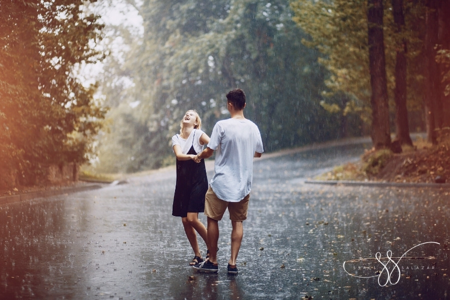couple laughing and dancing in the park in the rain