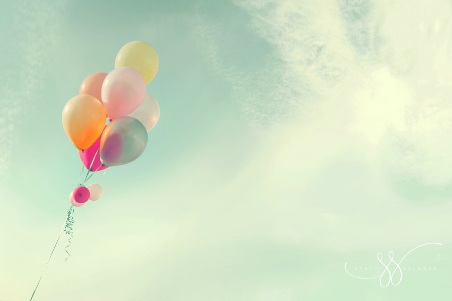 colorful balloons and ribbon floating in a cloudy vintage sky