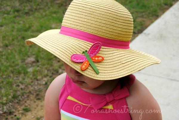 toddler looing sad under a straw sun hat