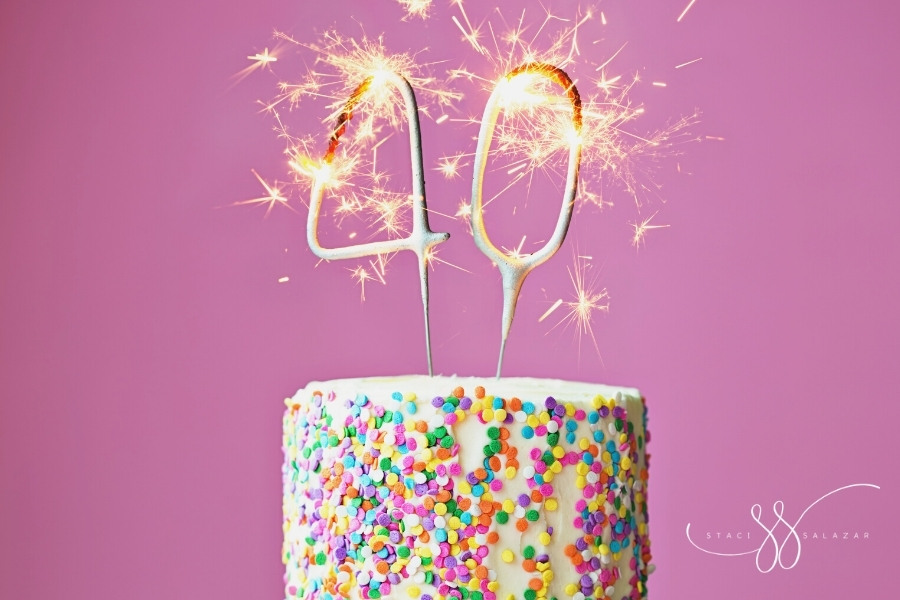 40th birthday cake with sparklers and confetti isolated on a pink background