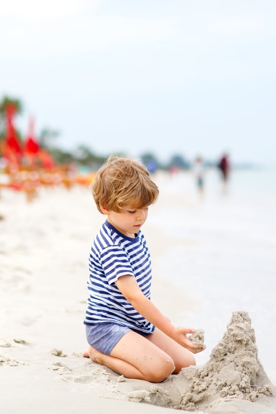 Easy Beach Crafts To Make This Summer boy making sand castle on a beach