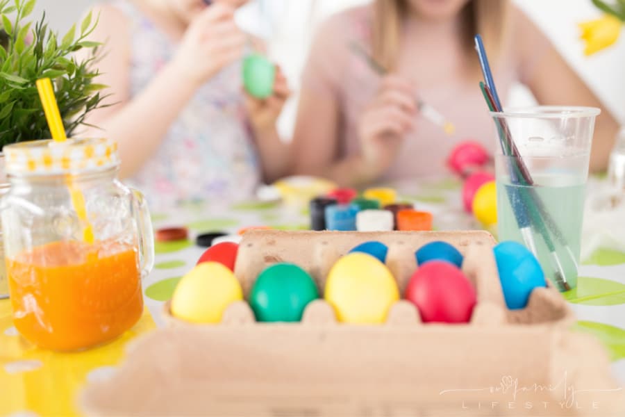 happy sisters painting colorful Easter eggs