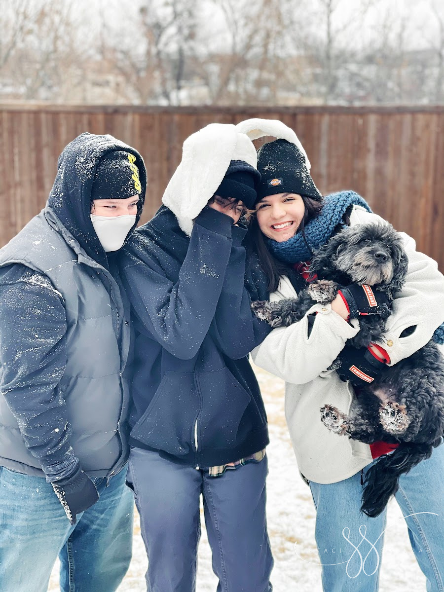 three teens and a mini goldendoodle standing in the snow